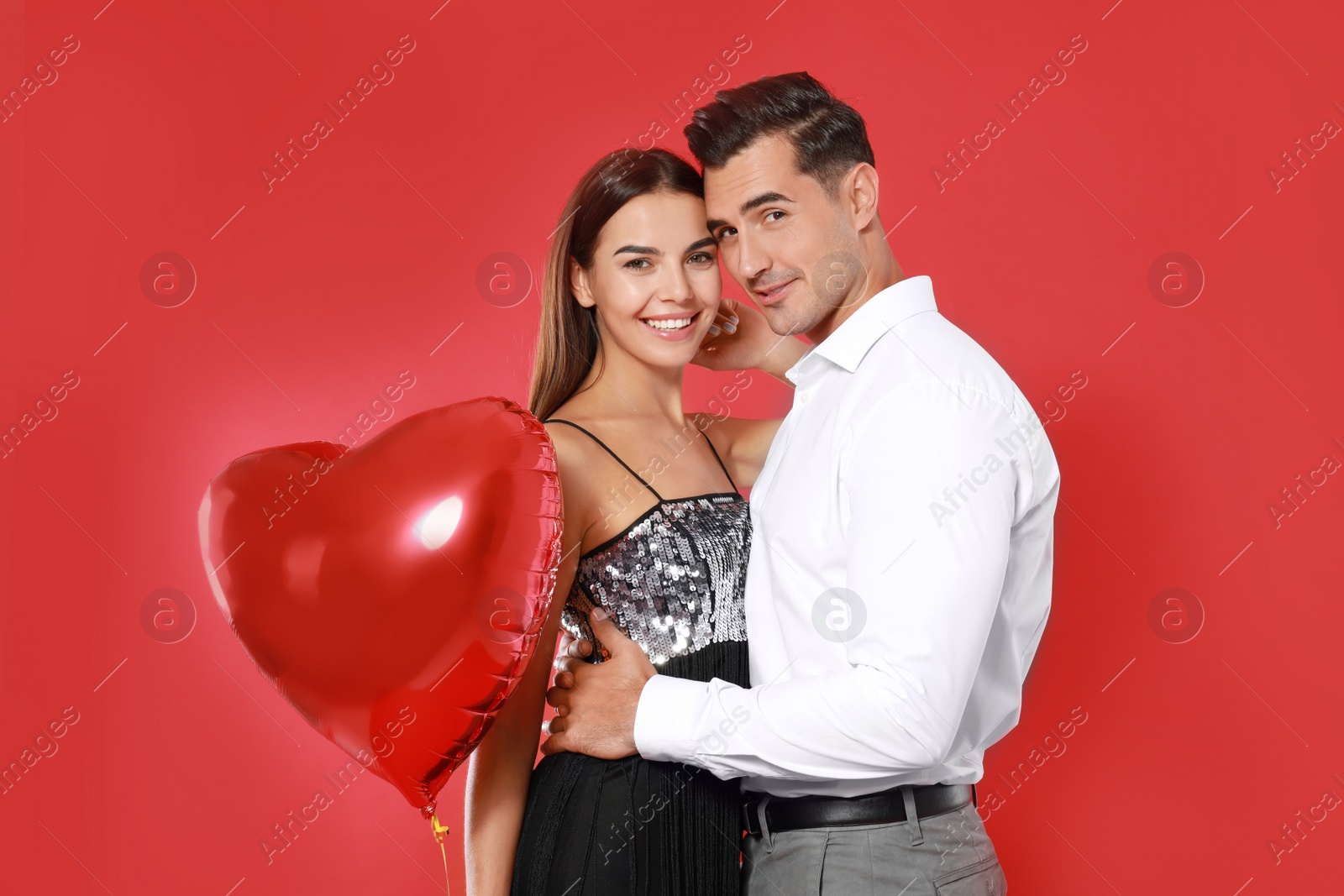 Photo of Beautiful couple with heart shaped balloon on red background