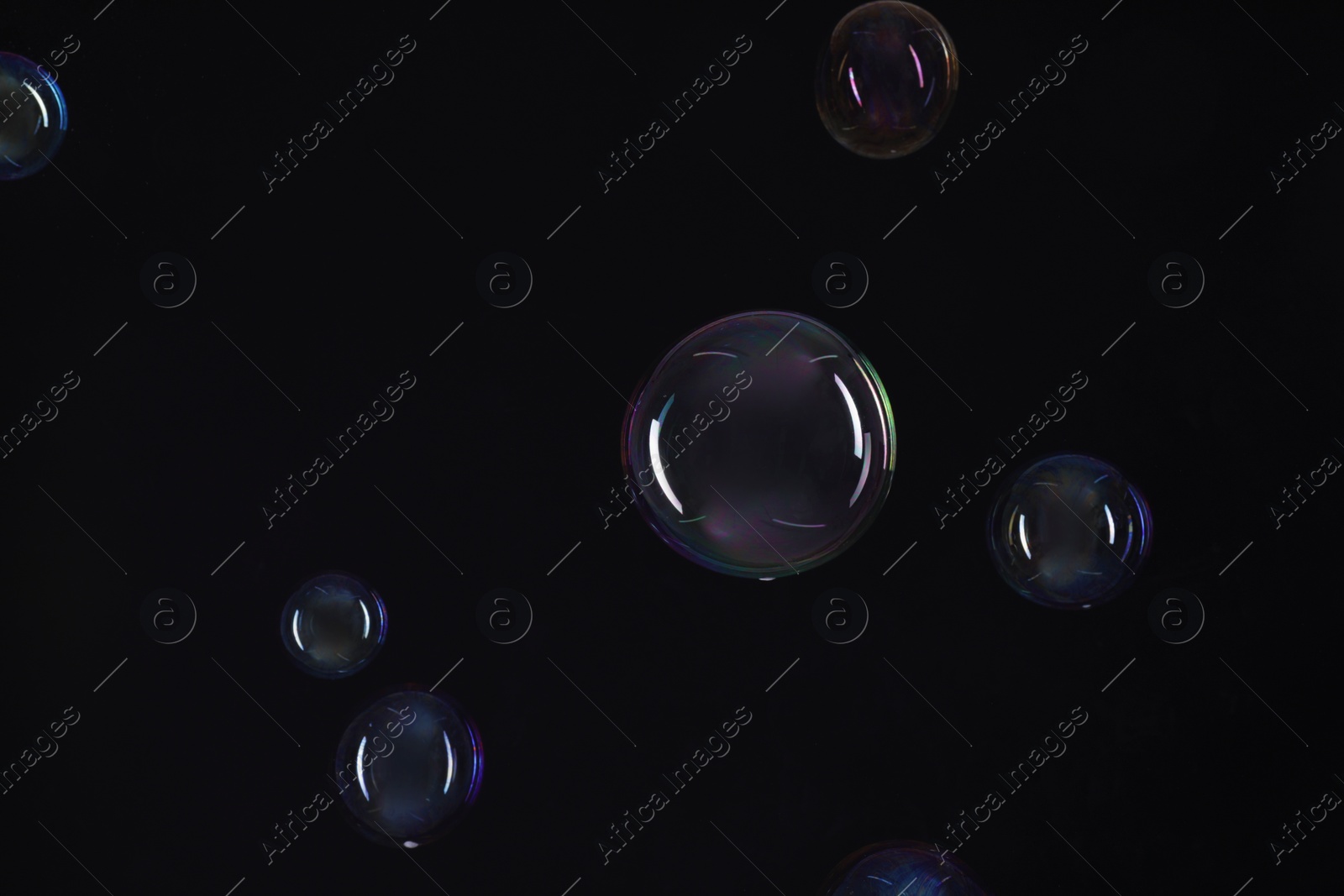 Photo of Many beautiful soap bubbles on black background