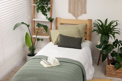 Photo of Large comfortable bed and potted houseplants in stylish bedroom. Interior design