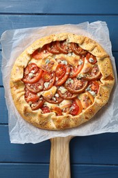 Tasty galette with tomato and cheese (Caprese galette) on blue wooden table, top view