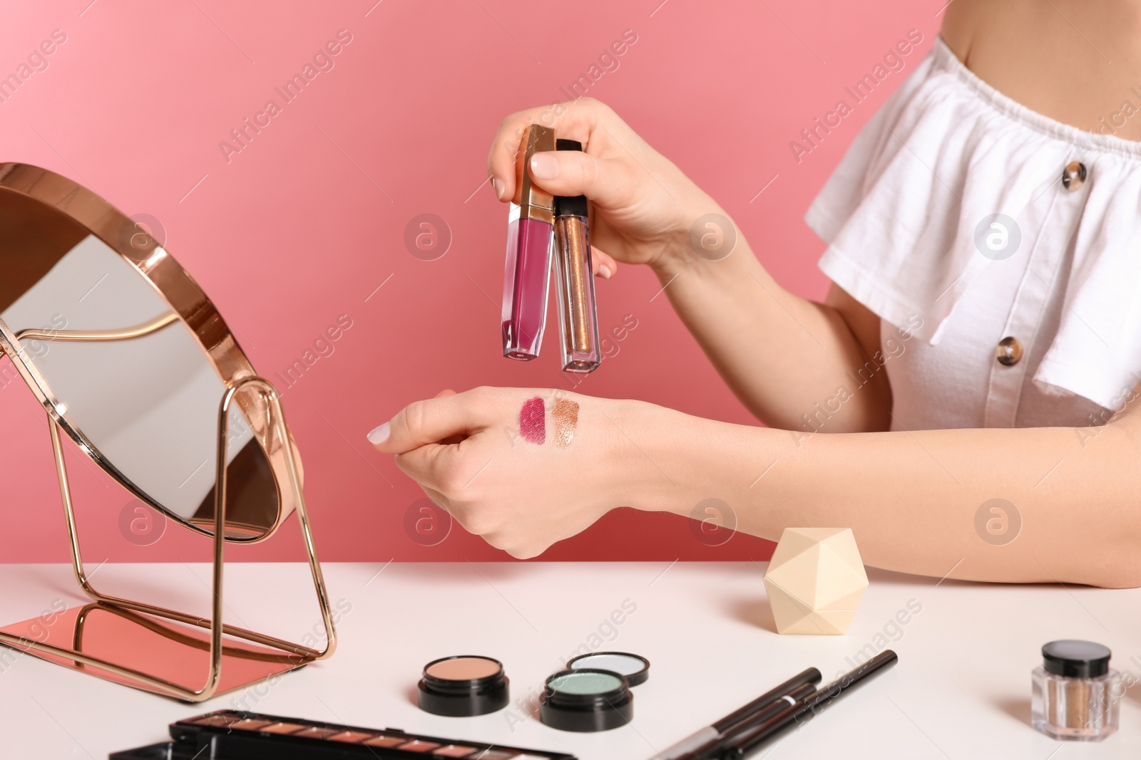 Photo of Beauty blogger with lipgloss and eyeshadow on pink background, closeup