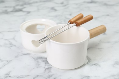 Photo of Fondue set on white marble table, closeup