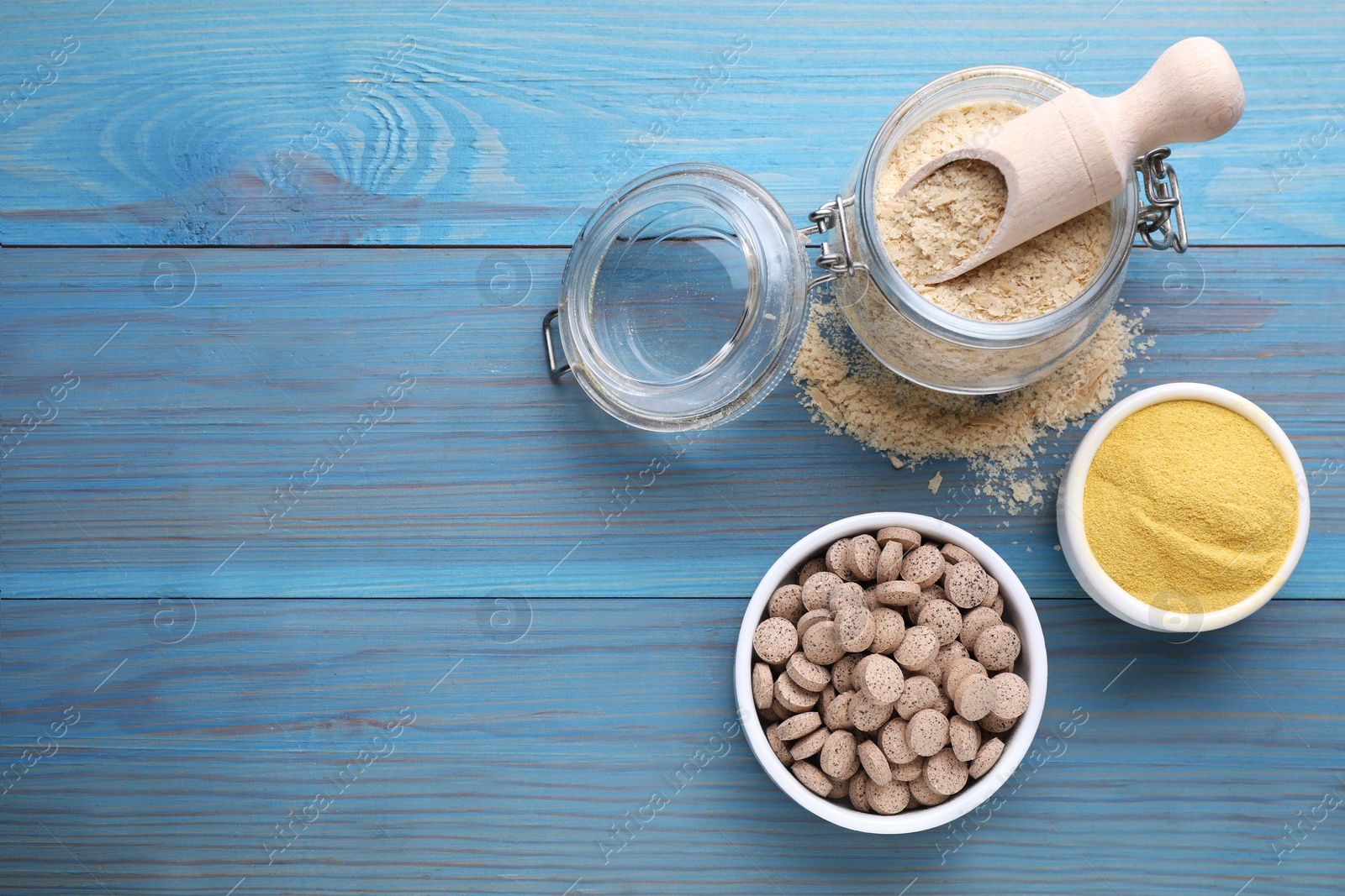 Photo of Different types of brewer's yeast on light blue wooden table, flat lay. Space for text