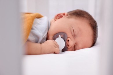 Photo of Cute newborn baby with pacifier sleeping on bed, closeup