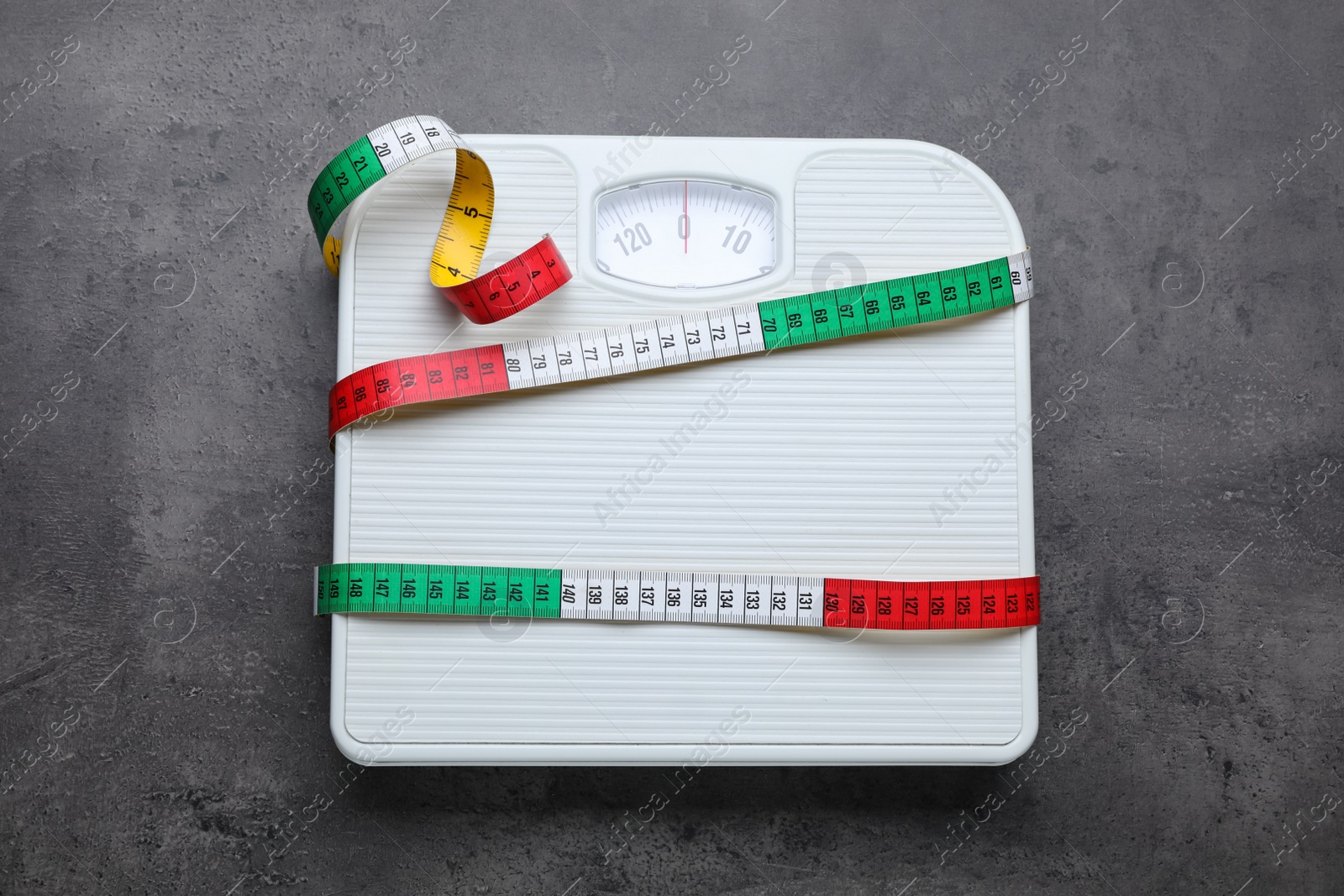 Photo of Scales and measuring tape on grey background, top view