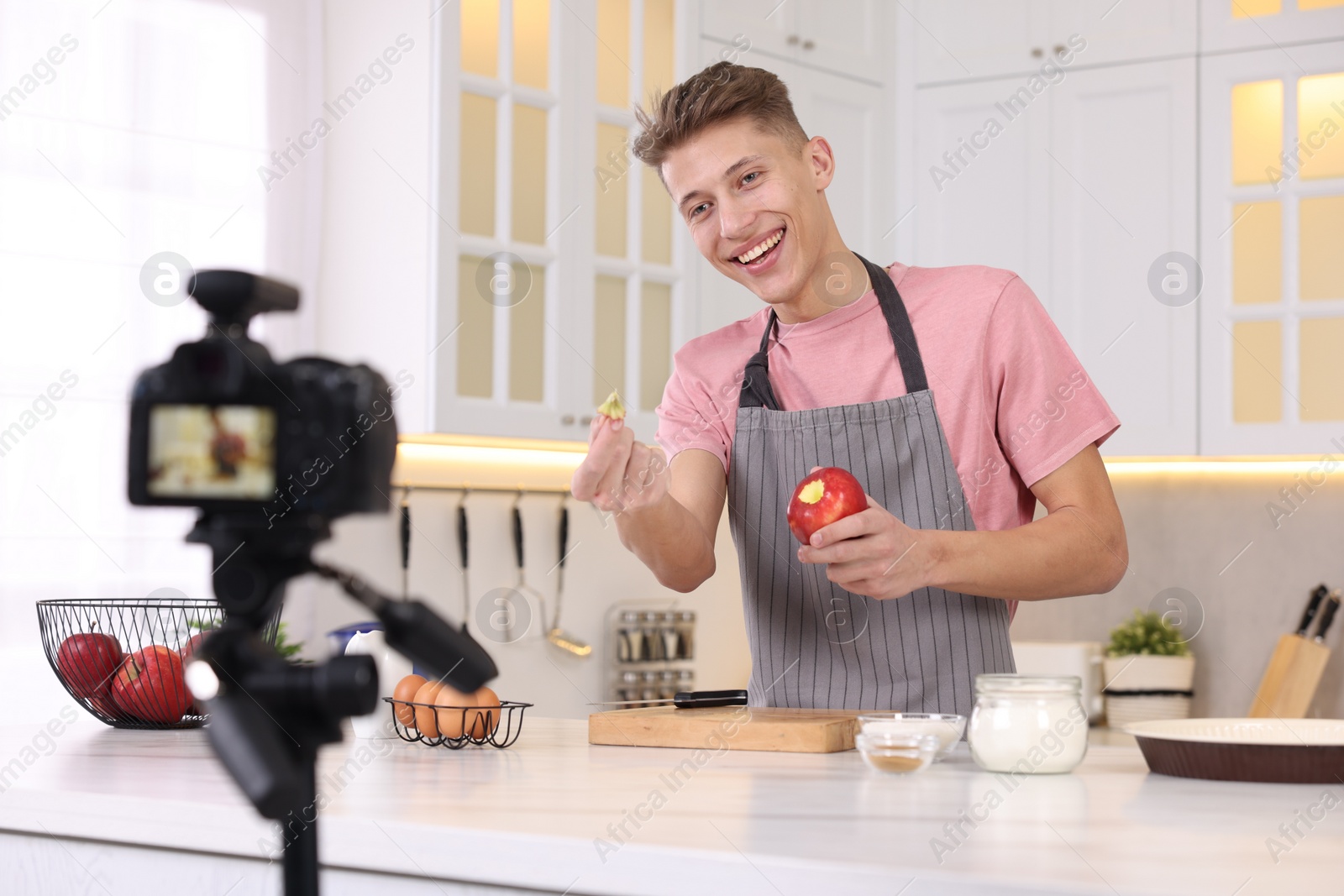 Photo of Smiling food blogger explaining something while recording video in kitchen