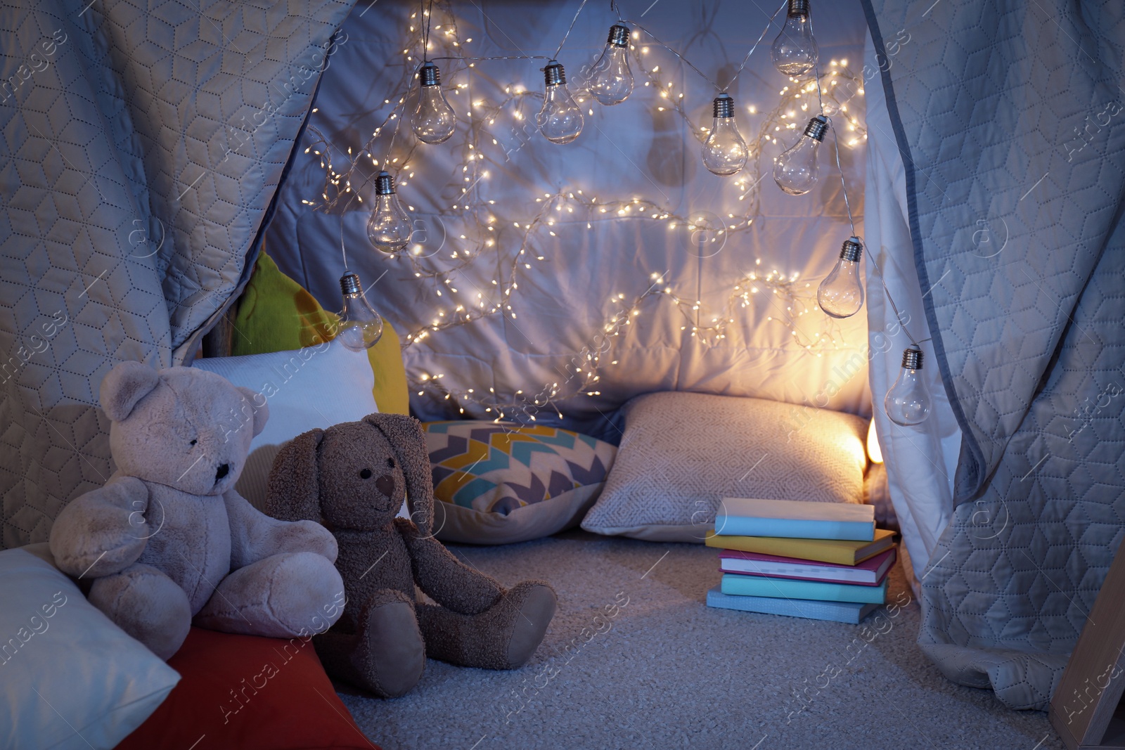 Photo of Play tent with toys and pillows indoors, closeup. Modern children's room interior