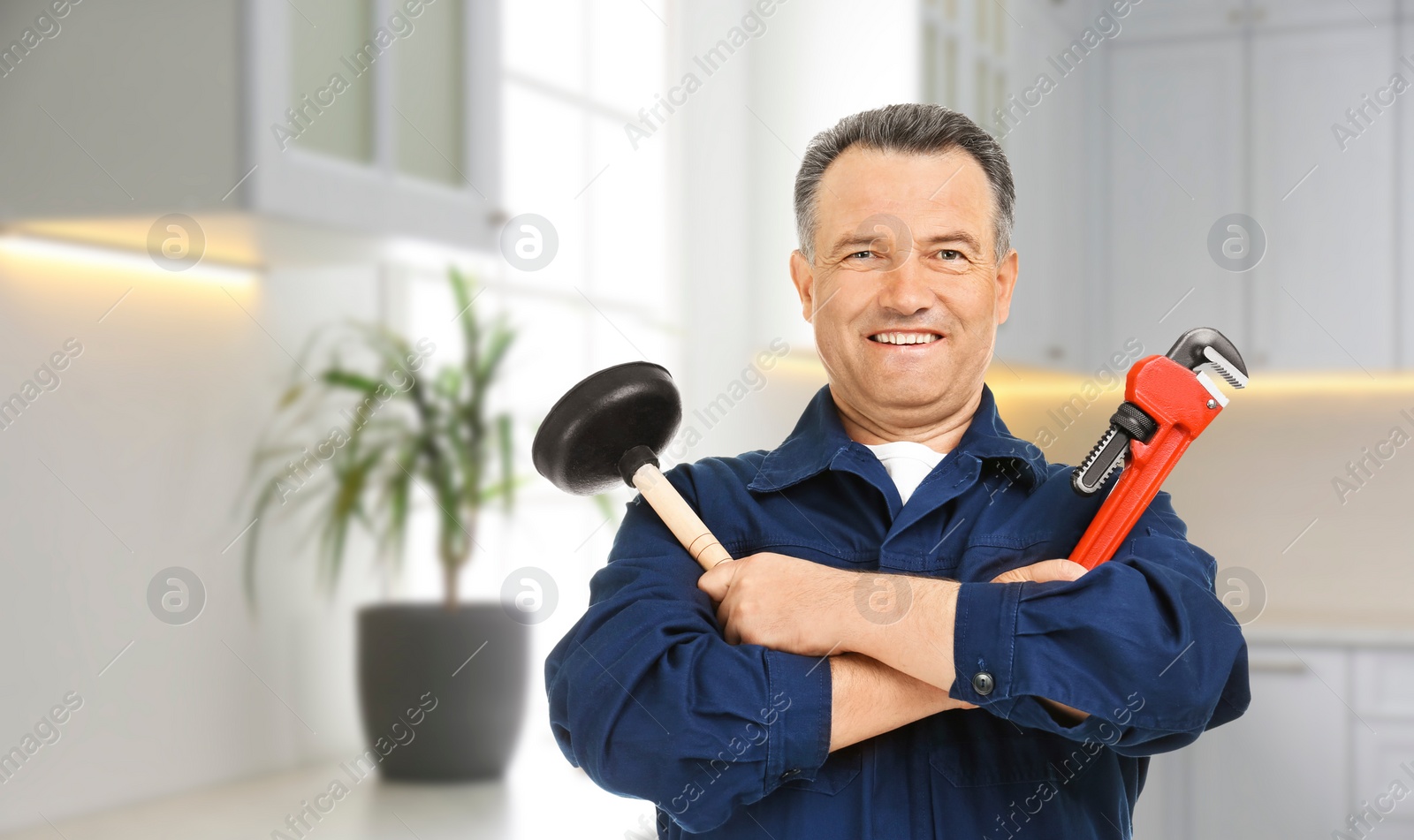 Image of Plumber with pipe wrench and force cup in kitchen, space for text