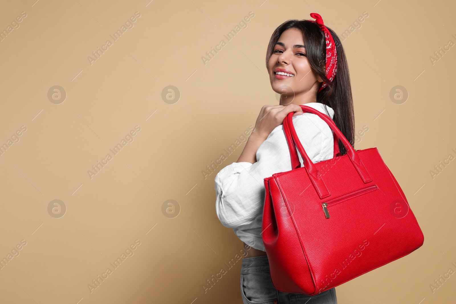 Photo of Young woman with stylish bag on beige background, space for text