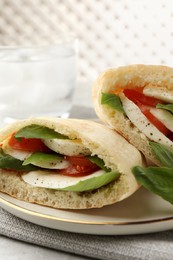 Photo of Delicious pita sandwich with mozzarella, tomatoes and basil on table, closeup