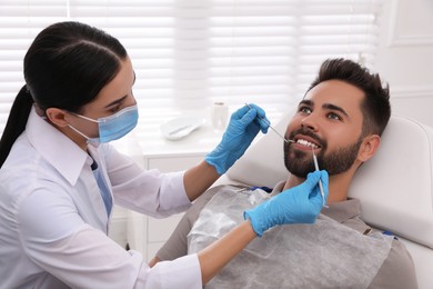 Photo of Dentist examining young man's teeth in modern clinic