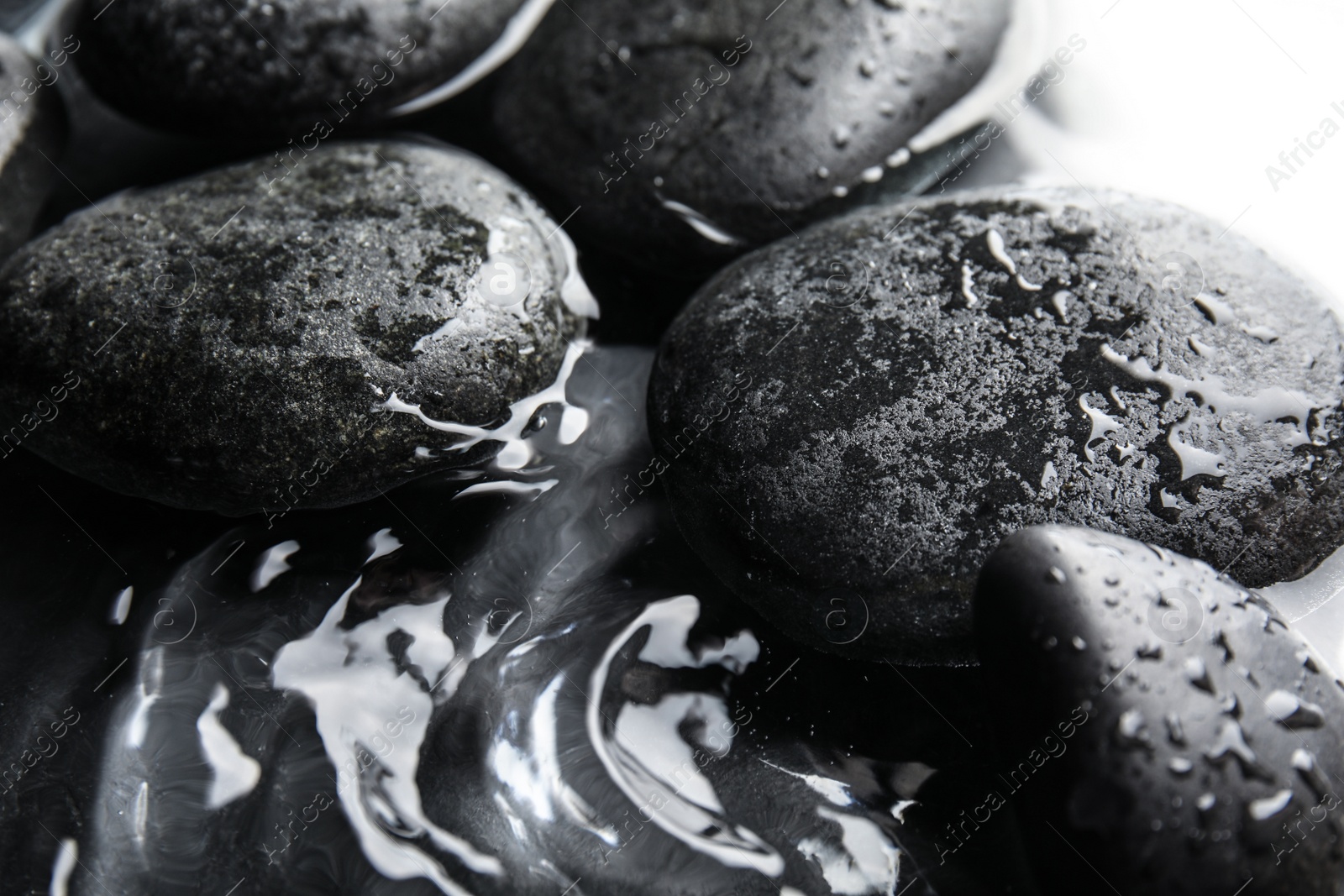 Photo of Stones in water on dark background, closeup. Zen lifestyle