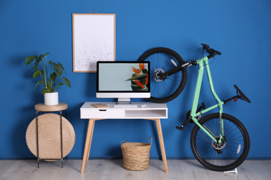 Photo of Stylish room interior with modern green bicycle and workplace
