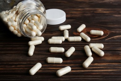 Photo of Glass medical bottle and pills on wooden table