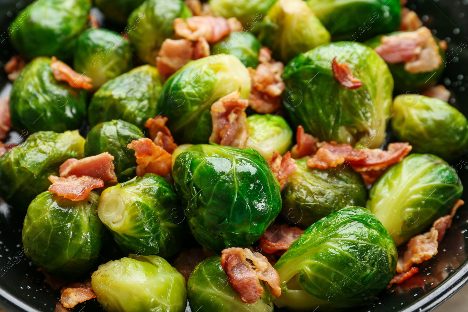 Photo of Frying pan of tasty roasted Brussels sprouts with bacon, closeup