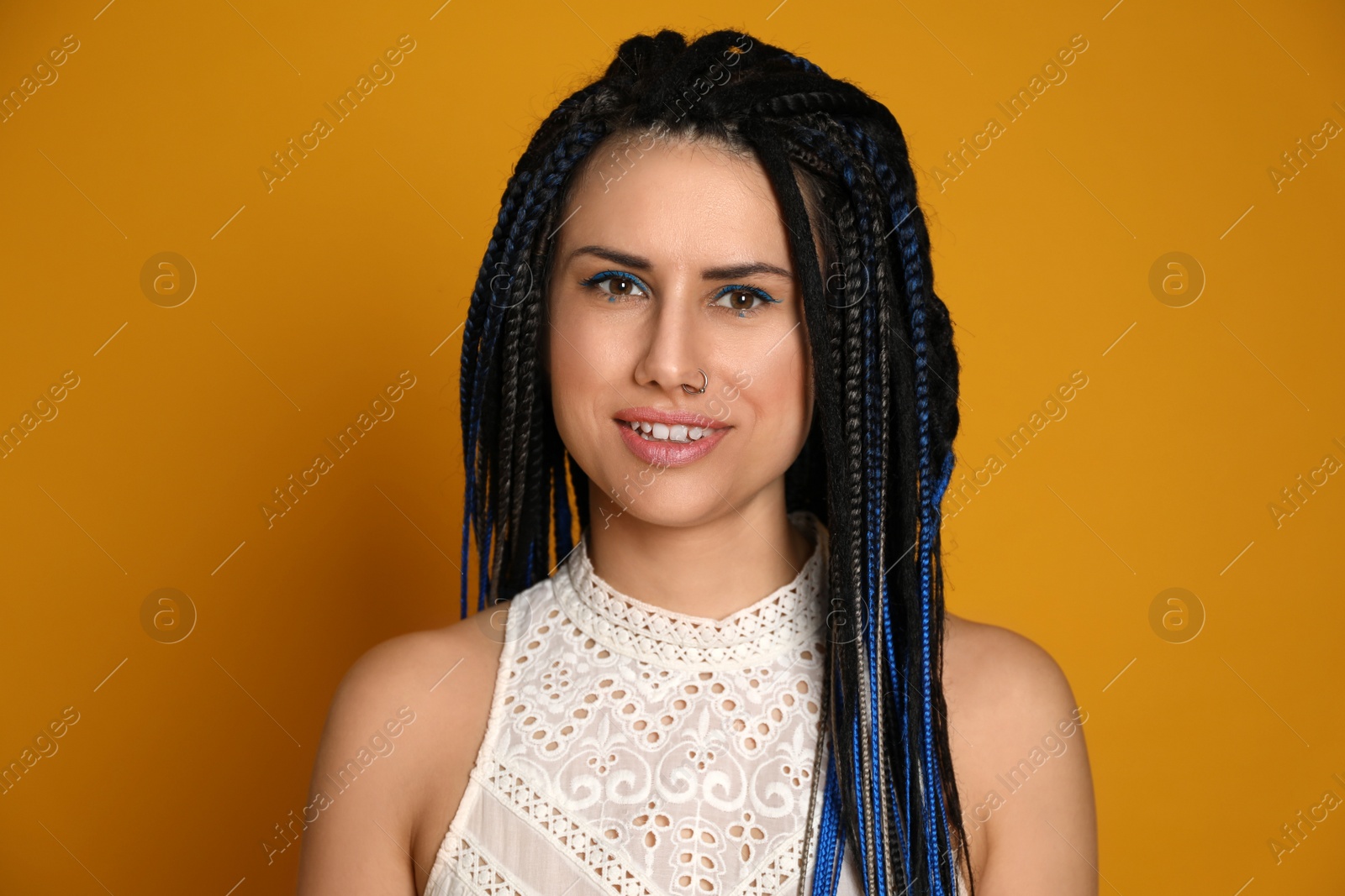 Photo of Beautiful young woman with nose piercing and dreadlocks on yellow background