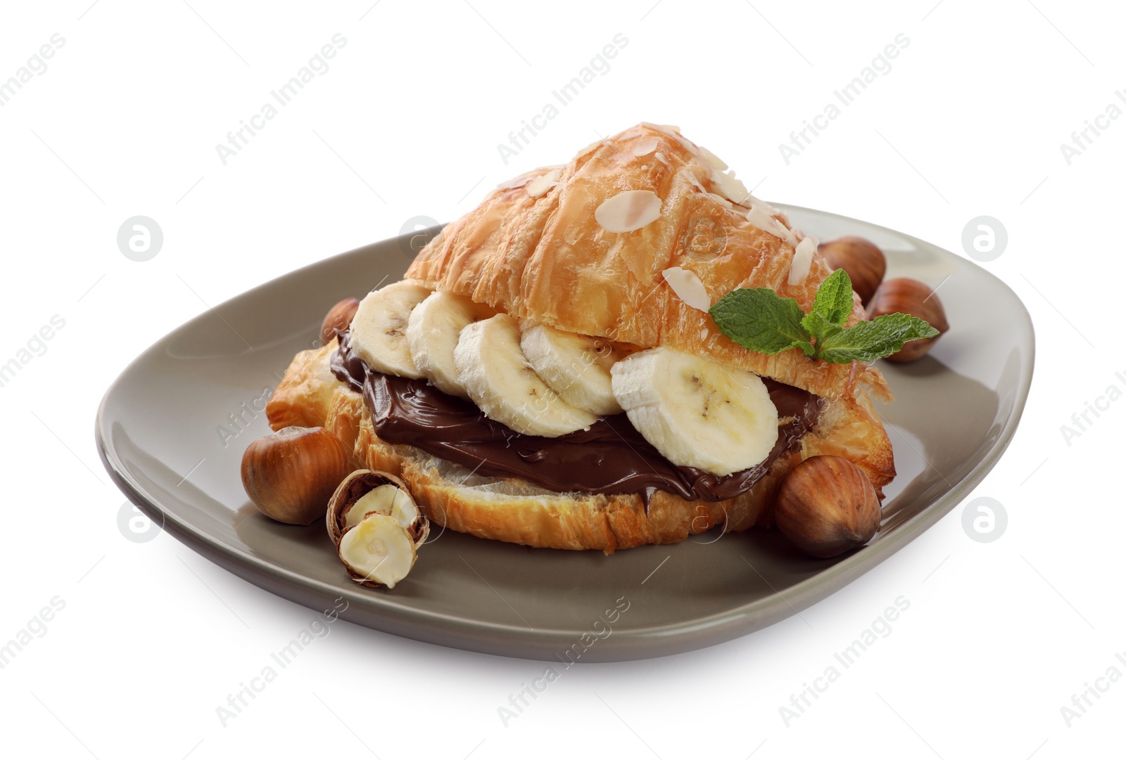 Photo of Delicious croissant with banana, chocolate and hazelnuts isolated on white