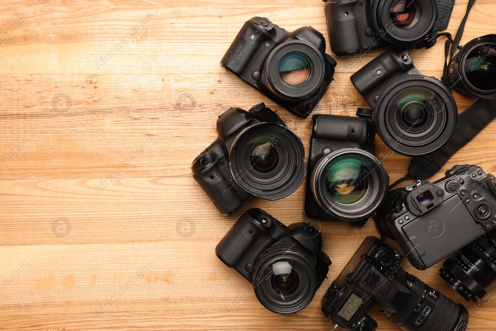 Photo of Modern different cameras on wooden table, flat lay. Space for text