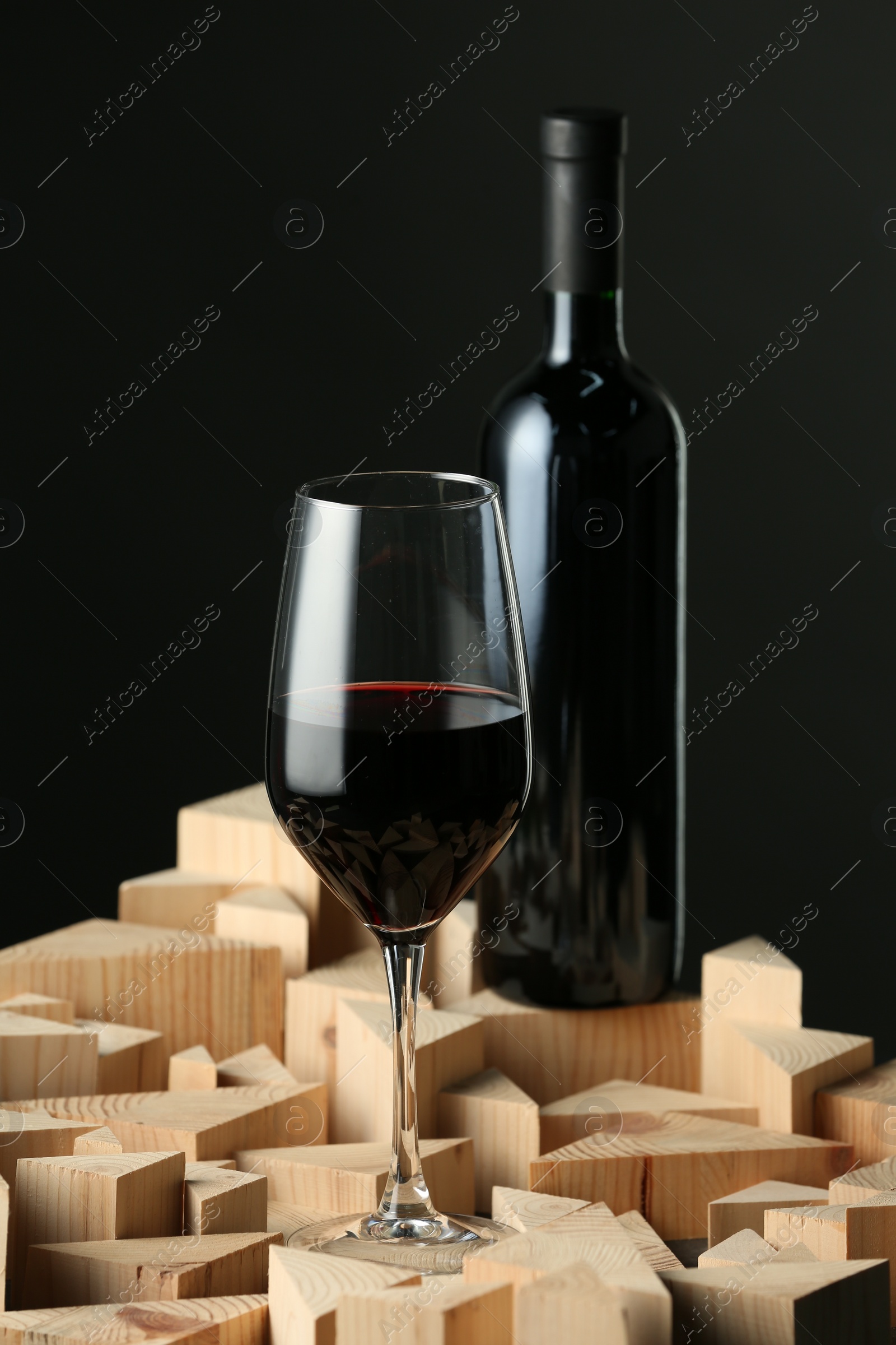 Photo of Stylish presentation of red wine in bottle and wineglass on black background
