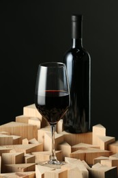 Stylish presentation of red wine in bottle and wineglass on black background