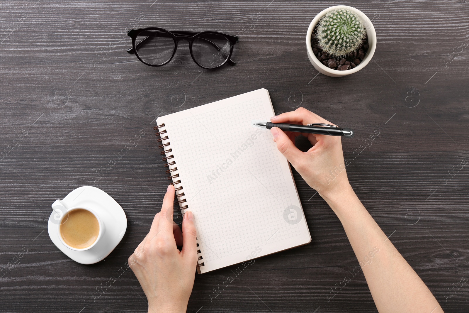 Photo of Woman with notebook and pen at grey wooden table, top view. Space for text