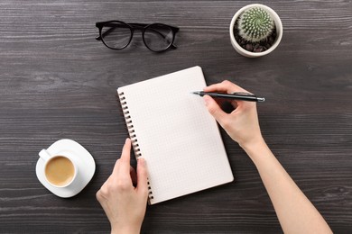 Woman with notebook and pen at grey wooden table, top view. Space for text