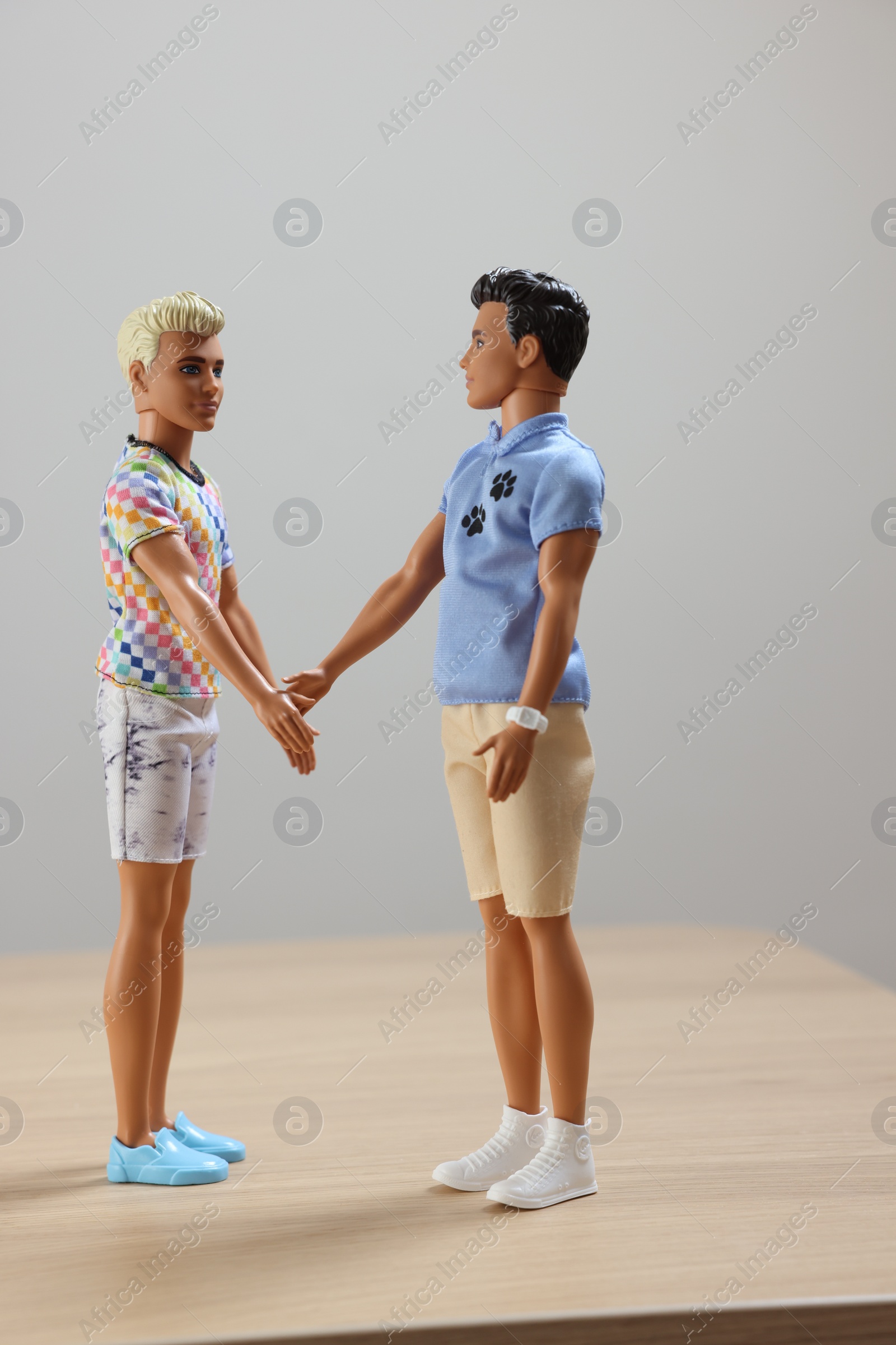 Photo of Leiden, Netherlands - September 20, 2023: Stylish Ken dolls on wooden table against light gray background