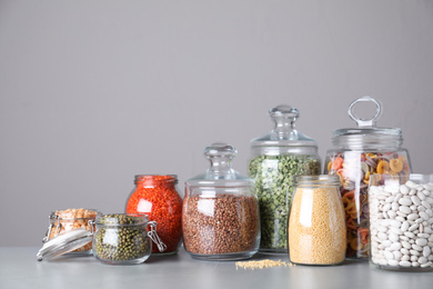 Photo of Jars with different cereals on grey table