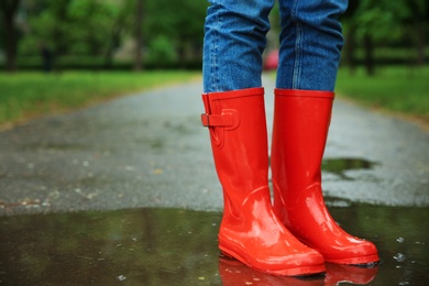 Photo of Woman with rubber boots in puddle, closeup. Rainy weather