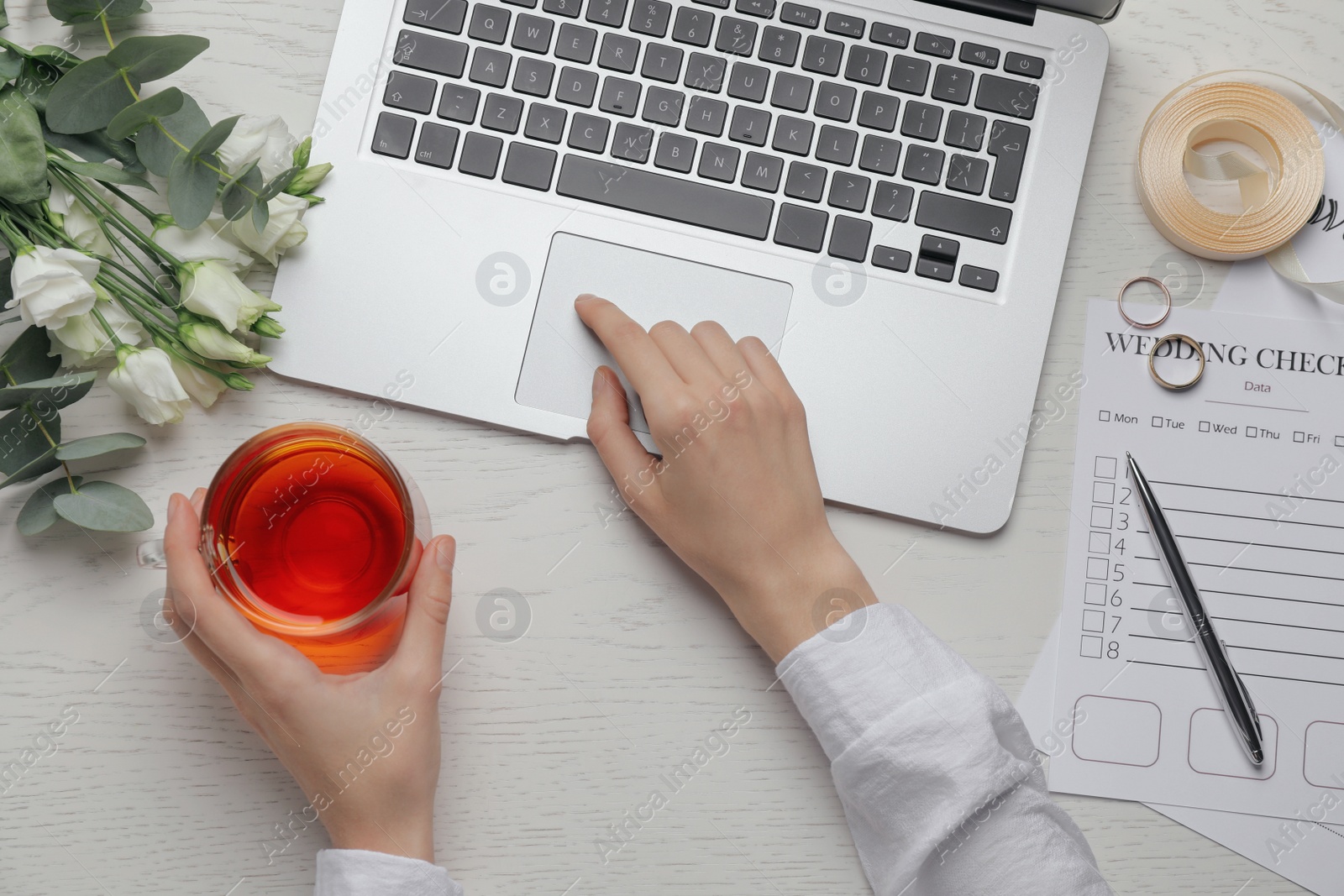 Photo of Woman with laptop and Wedding Checklist at white wooden table, top view