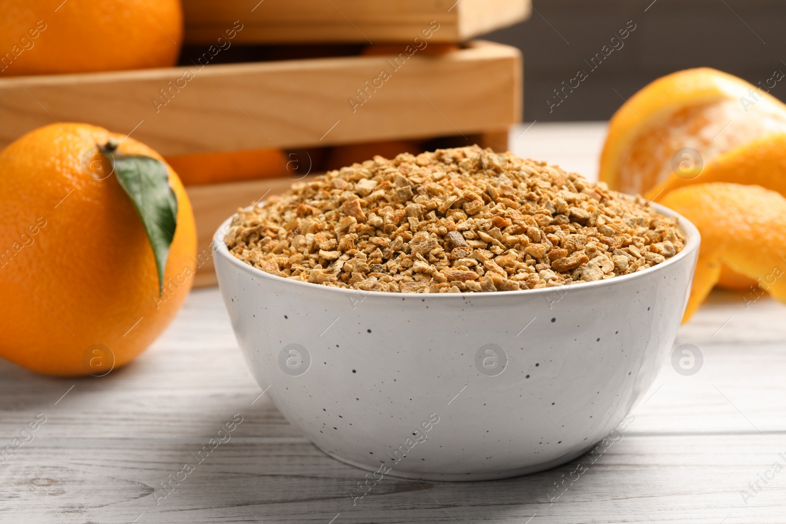 Photo of Bowl with dried orange seasoning zest and fruits on white wooden table, closeup