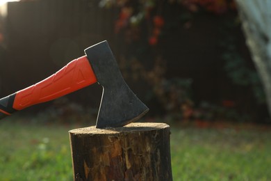Photo of Metal axe in wooden log on backyard, closeup