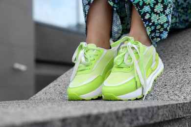 Photo of Woman wearing stylish sneakers outdoors, closeup. Space for text