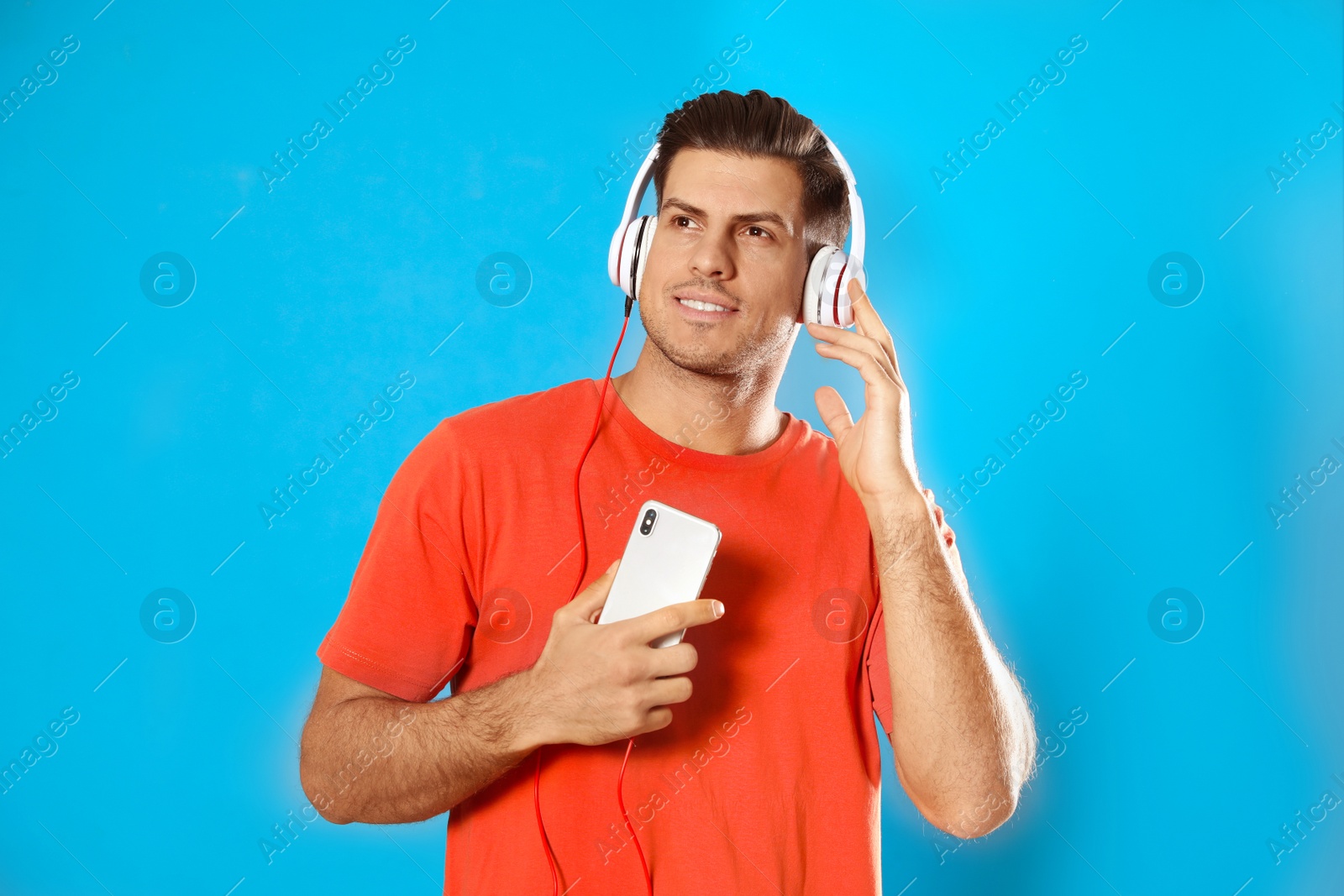 Photo of Man with mobile phone listening to audiobook on light blue background