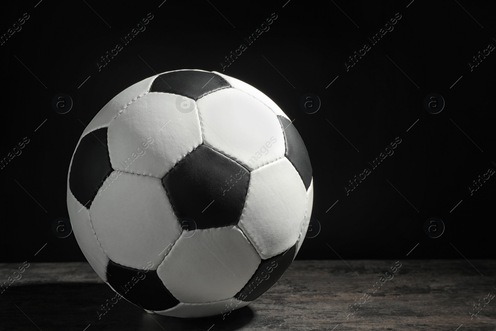 Photo of New soccer ball on table against dark background. Football equipment