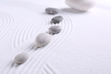 Photo of Zen garden stones on white sand with pattern, space for text