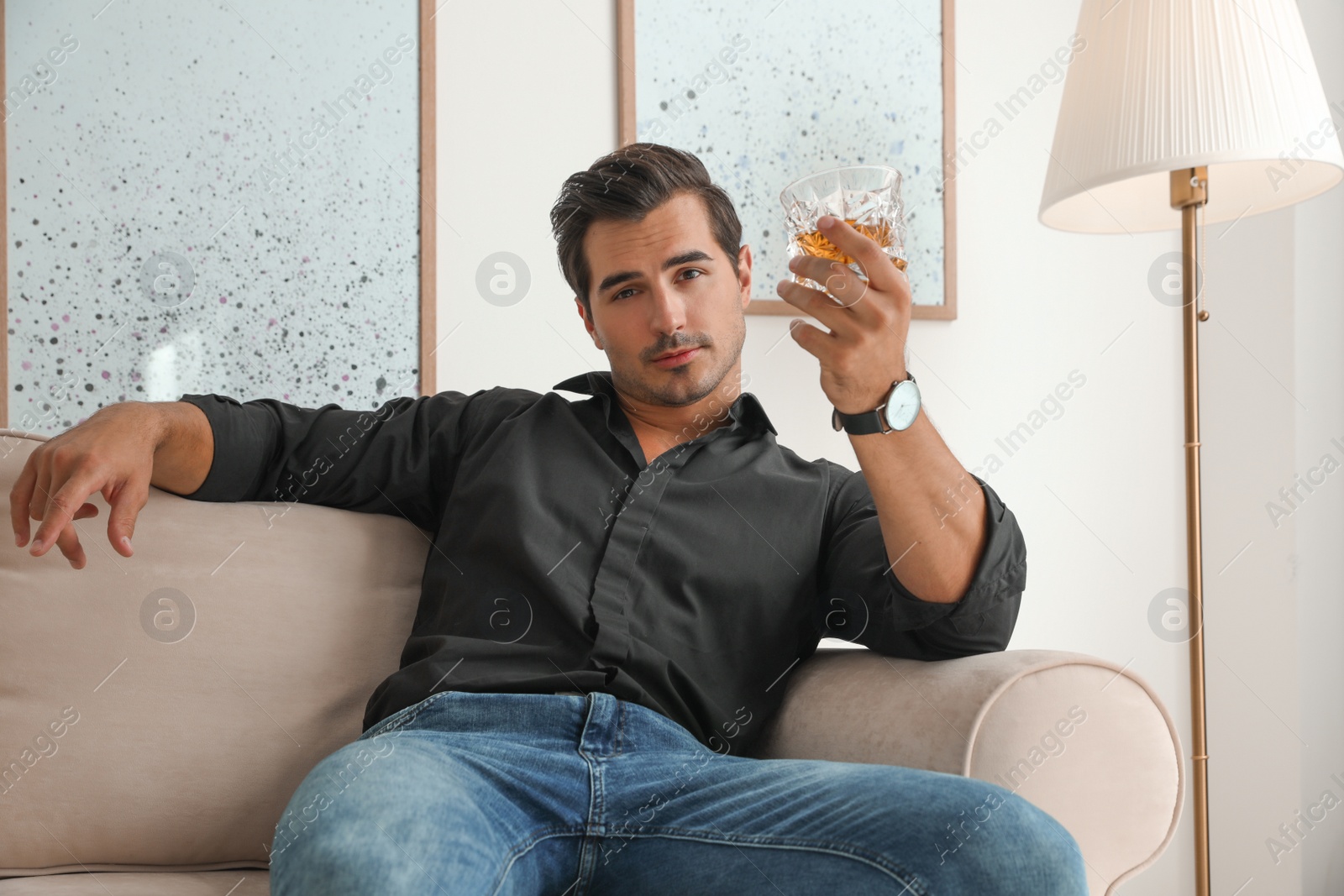 Photo of Young man with glass of whiskey at home