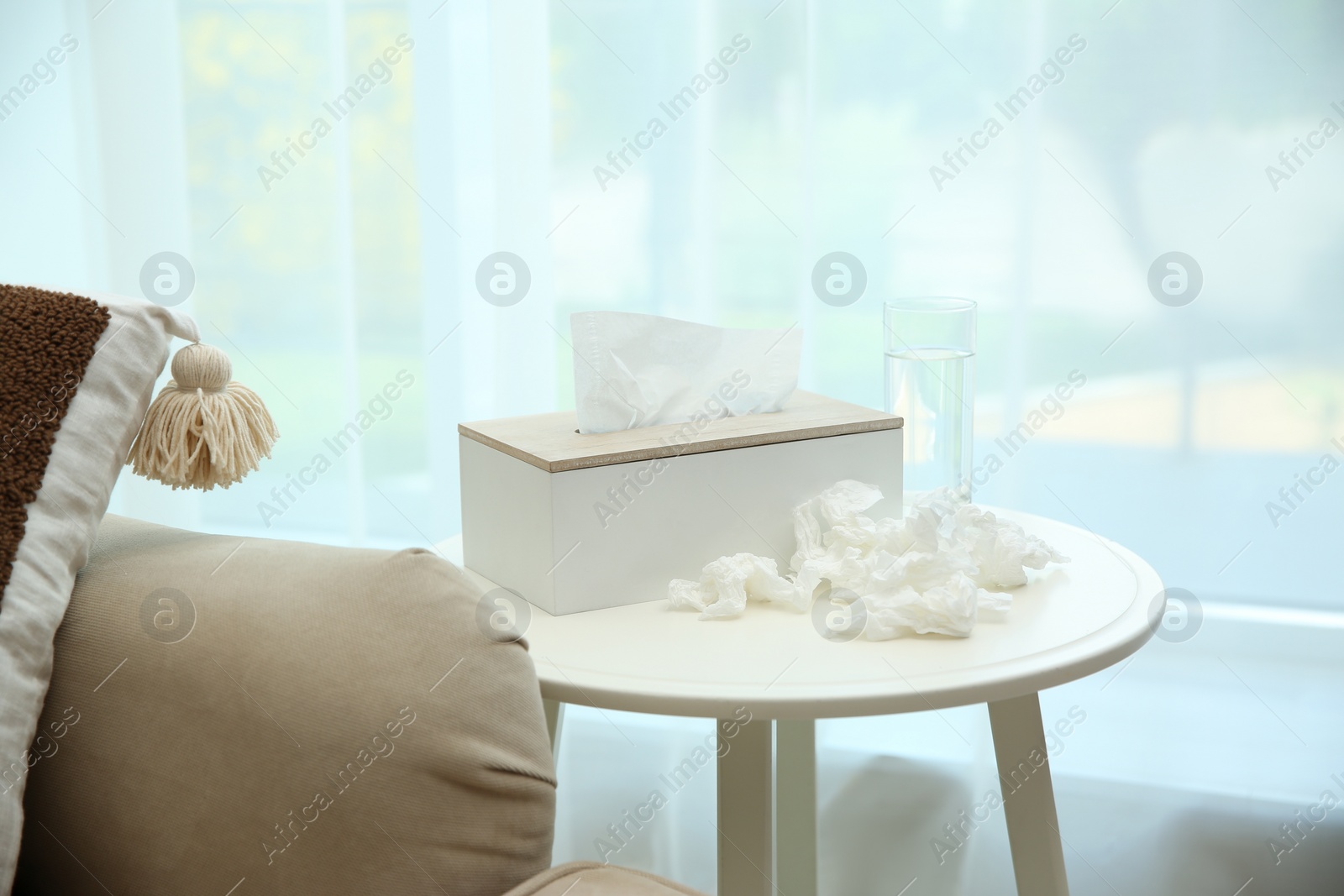 Photo of Used paper tissues, holder and water on table indoors