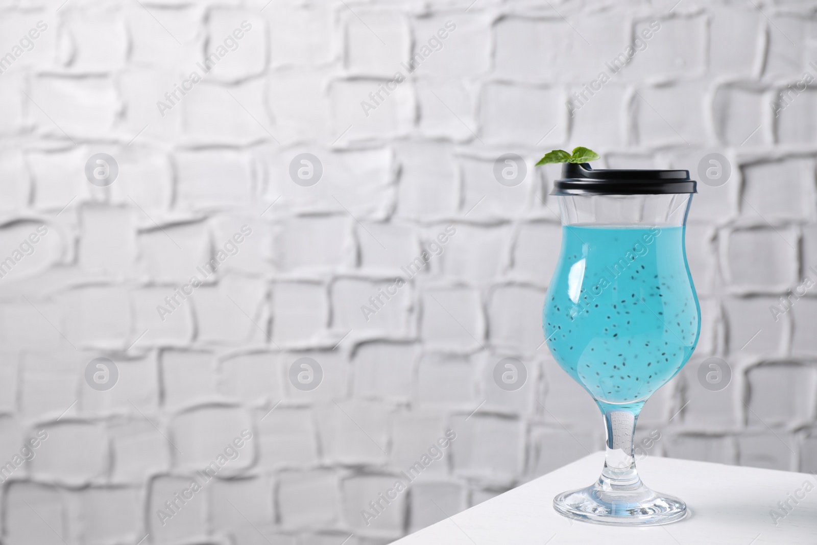 Photo of Light blue drink in glass with lid on white table, space for text