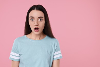 Photo of Portrait of surprised woman on pink background. Space for text