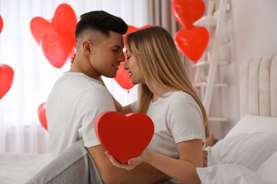 Photo of Lovely couple with gift in room. Valentine's day celebration