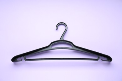 Empty black hanger on lilac background, top view