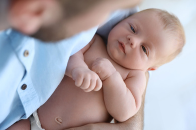 Photo of Father holding his cute newborn baby at home, closeup