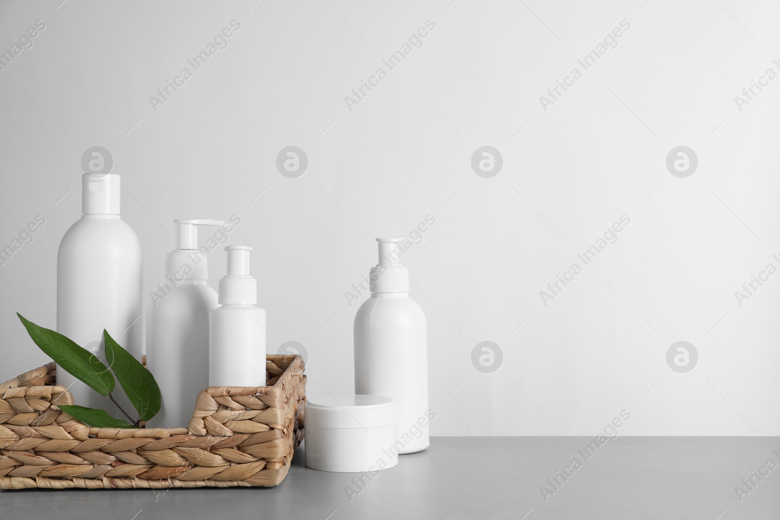 Photo of Different cosmetic products and leaves on grey table. Space for text