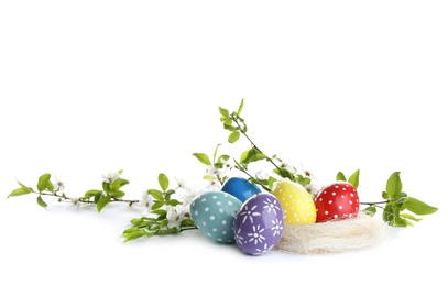 Photo of Painted Easter eggs and blossoming branches on white background