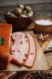 Photo of Delicious smoked bacon with parsley and pepper on wooden board, closeup