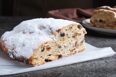 Traditional Christmas Stollen with icing sugar on grey table