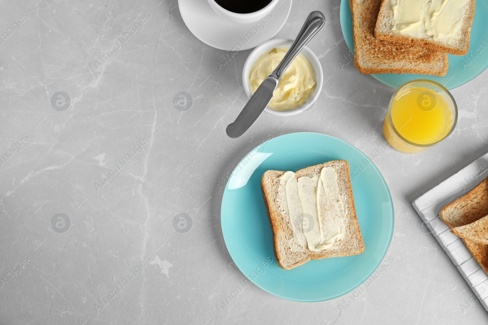 Photo of Tasty bread with butter served for breakfast on grey marble table, top view. Space for text