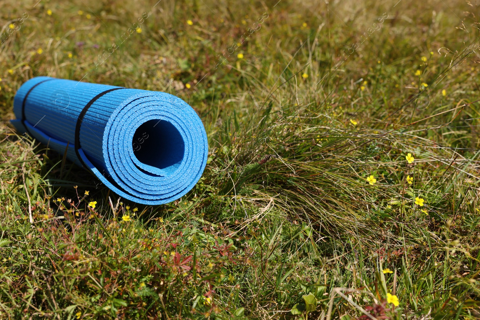 Photo of Rolled blue soft sleeping pad on grass, space for text