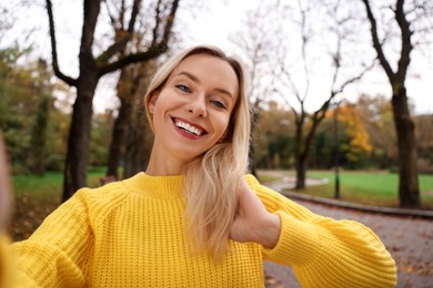 Portrait of happy woman taking selfie in autumn park